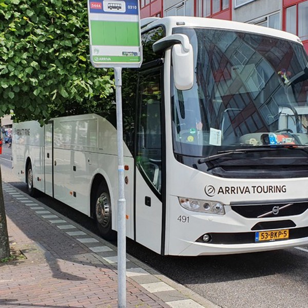 Witte Arriva Touringbus staat bij bushalte geparkeerd.