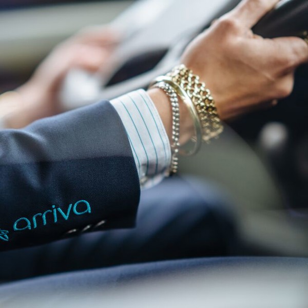 Handen van een Arriva-buschauffeur van het stuur, hij draagt ook verschillende armbanden.