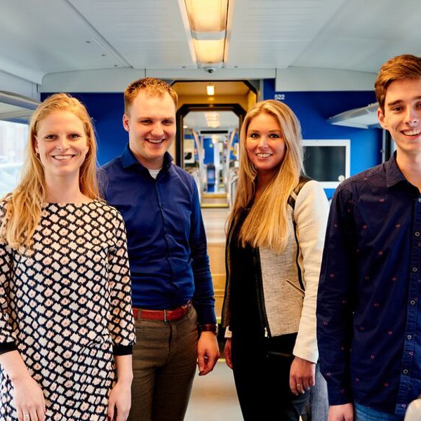 Vier jonge collega's staan lachend in een Arriva-trein
