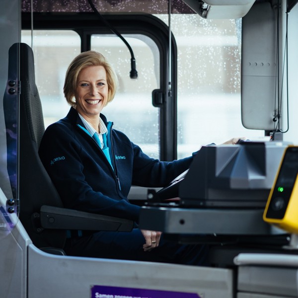 Buschauffeur Carola zit lachend achter het stuur van haar Arriva-bus. Buschauffeur Carola zit lachend achter het stuur van haar Arriva-bus.