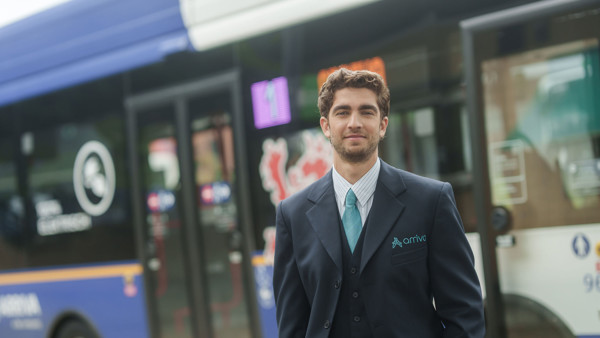 Een buschauffeur in Arriva-uniform staat voor een bus, met lijnnummer 1 en Arriva duidelijk zichtbaar op de achtergrond. Een buschauffeur in Arriva-uniform staat voor een bus, met lijnnummer 1 en Arriva duidelijk zichtbaar op de achtergrond.