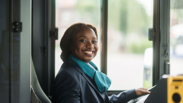 Buschauffeur in Arriva-uniform kijkt opzij en ze lacht naar de camera. Buschauffeur in Arriva-uniform kijkt opzij en ze lacht naar de camera.