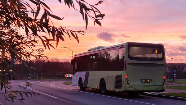 Arriva-bus rijdt op de weg onder een roze, oranje en paars gekleurde zonsondergang. Arriva-bus rijdt op de weg onder een roze, oranje en paars gekleurde zonsondergang.