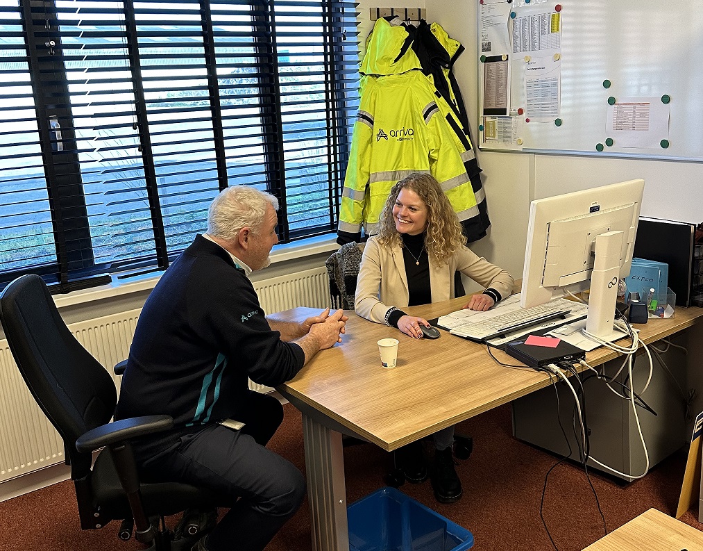 Stagiair Kitty zit achter haar computer en is in gesprek met een collega van Arriva.