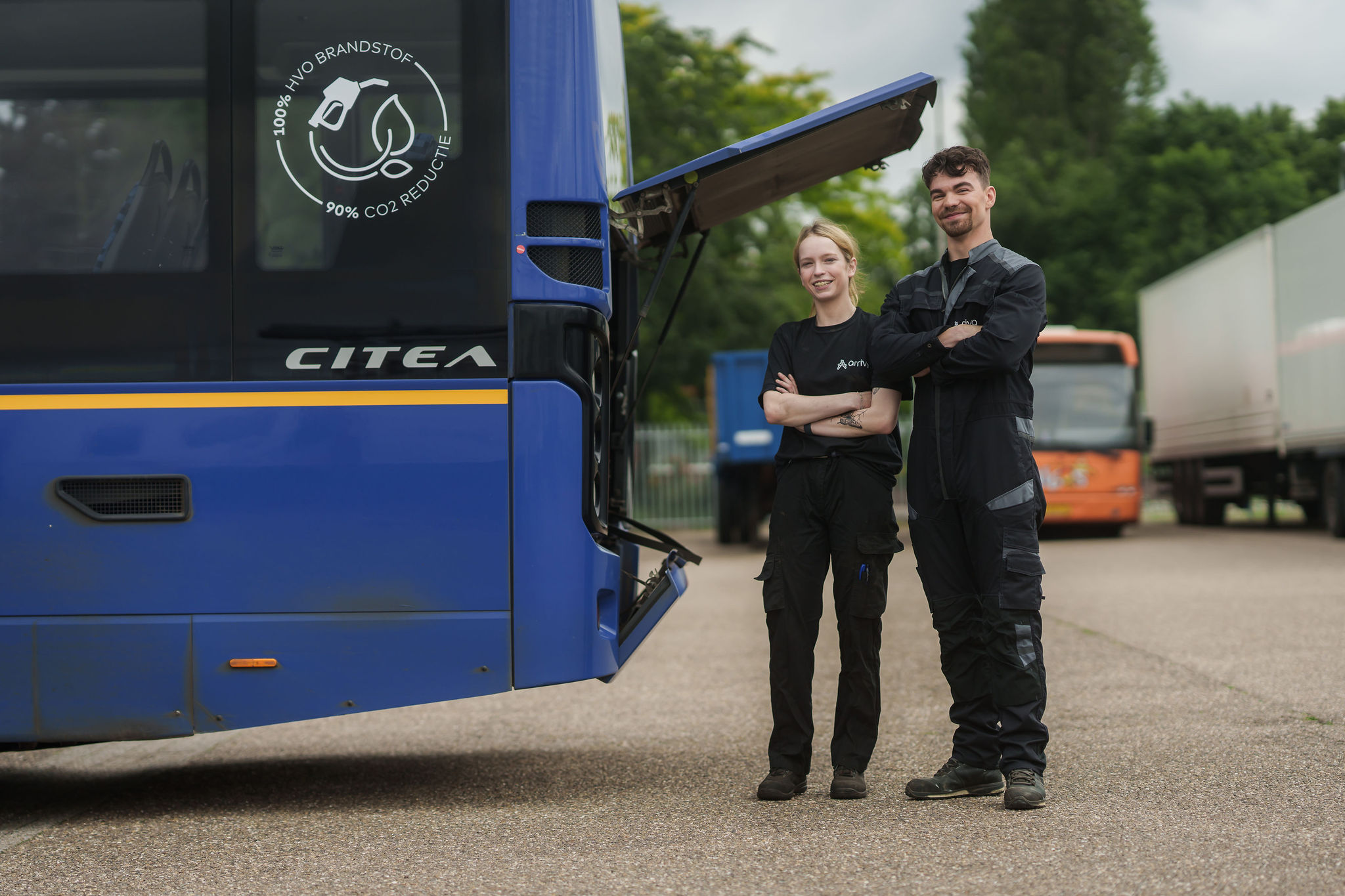 Twee monteurs van Arriva staan achter een bus bij de motor.