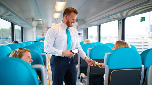 Mannelijke conducteur checkt het vervoersbewijs van een reiziger in een Arriva-trein.
