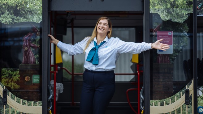 Buschauffeur van Arriva staat breed lachend met haar armen wijd in de deuropening van een bus. Buschauffeur van Arriva staat breed lachend met haar armen wijd in de deuropening van een bus.