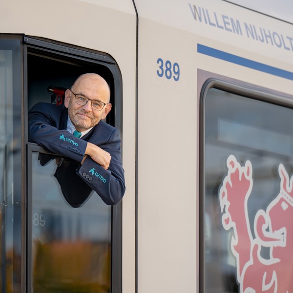 Machinist van middelbare leeftijd hangt uit het raam van een Arriva-trein Machinist van middelbare leeftijd hangt uit het raam van een Arriva-trein