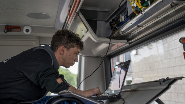 Monteur aan het werk in een Arriva bus, met behulp van een laptop.