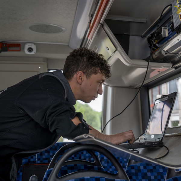 Monteur aan het werk in een Arriva bus, met behulp van een laptop.
