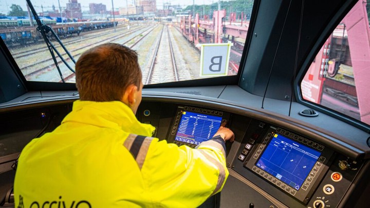 Een mannelijke machinist in uniform zit in de cabine, kijkt uit over het spoor en bestuurt de trein. Een mannelijke machinist in uniform zit in de cabine, kijkt uit over het spoor en bestuurt de trein.