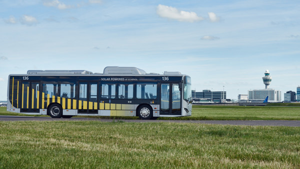 Elektrische Arriva-bus rijdt door een weiland onder een blauwe lucht met wolken. Op de achtergrond is Schiphol te zien. Elektrische Arriva-bus rijdt door een weiland onder een blauwe lucht met wolken. Op de achtergrond is Schiphol te zien.