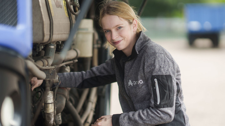 Jonge vrouw sleutelt aan een bus van Arriva en kijkt in de camera Jonge vrouw sleutelt aan een bus van Arriva en kijkt in de camera