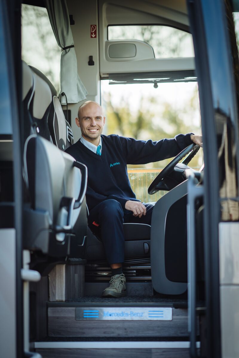 Arriva touringcarchauffeur zit relaxt achter stuur.
