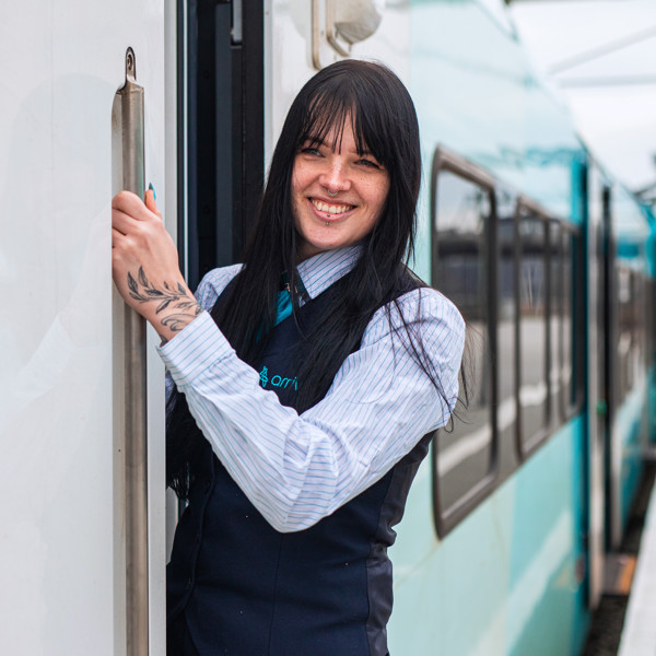 Machinist Shannon stapt lachend in de cabine van een Arriva trein en kijkt naar buiten. Machinist Shannon stapt lachend in de cabine van een Arriva trein en kijkt naar buiten.