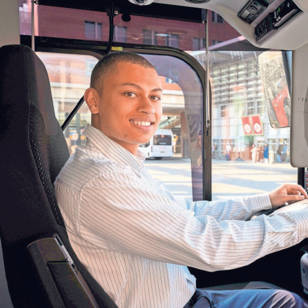 Studentchauffeur Tyrese glimlachend achter het stuur van de bus Studentchauffeur Tyrese glimlachend achter het stuur van de bus