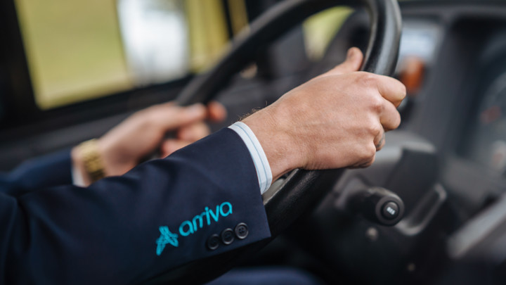 De handen van een buschauffeur aan het stuur van zijn bus, er is nog 'Arriva' te zien op de mouw van zijn jasje. De handen van een buschauffeur aan het stuur van zijn bus, er is nog 'Arriva' te zien op de mouw van zijn jasje.