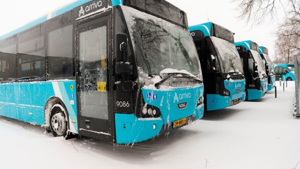 Vier blauwe Arriva-bussen op een rij in de sneeuw.