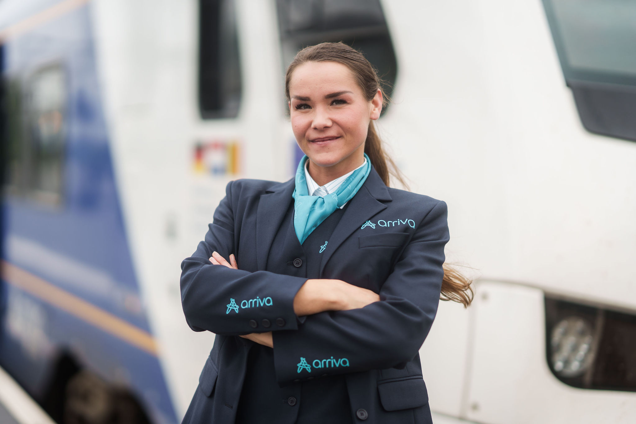 Machinist van Arriva staat lachend met de armen over elkaar voor haar trein.