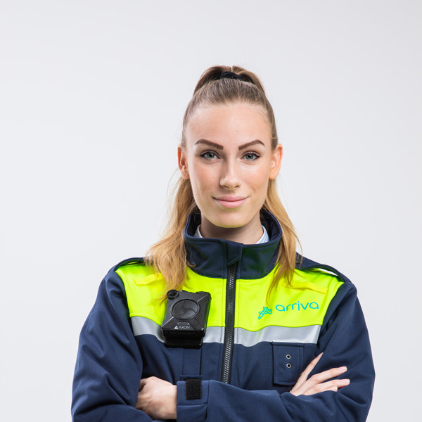 Een jonge vrouwelijke BOA (Buitengewoon Opsporingsambtenaar) kijkt met haar armen over elkaar in de camera, gekleed in een Arriva-uniform.