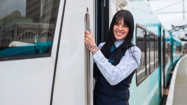 Vrouwelijke machinist staat in de deur van een Arrivatrein en lacht Vrouwelijke machinist staat in de deur van een Arrivatrein en lacht