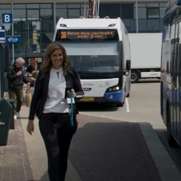Een vrouw loopt langs een Arriva bus. Op de achtergrond staat nog een bus.